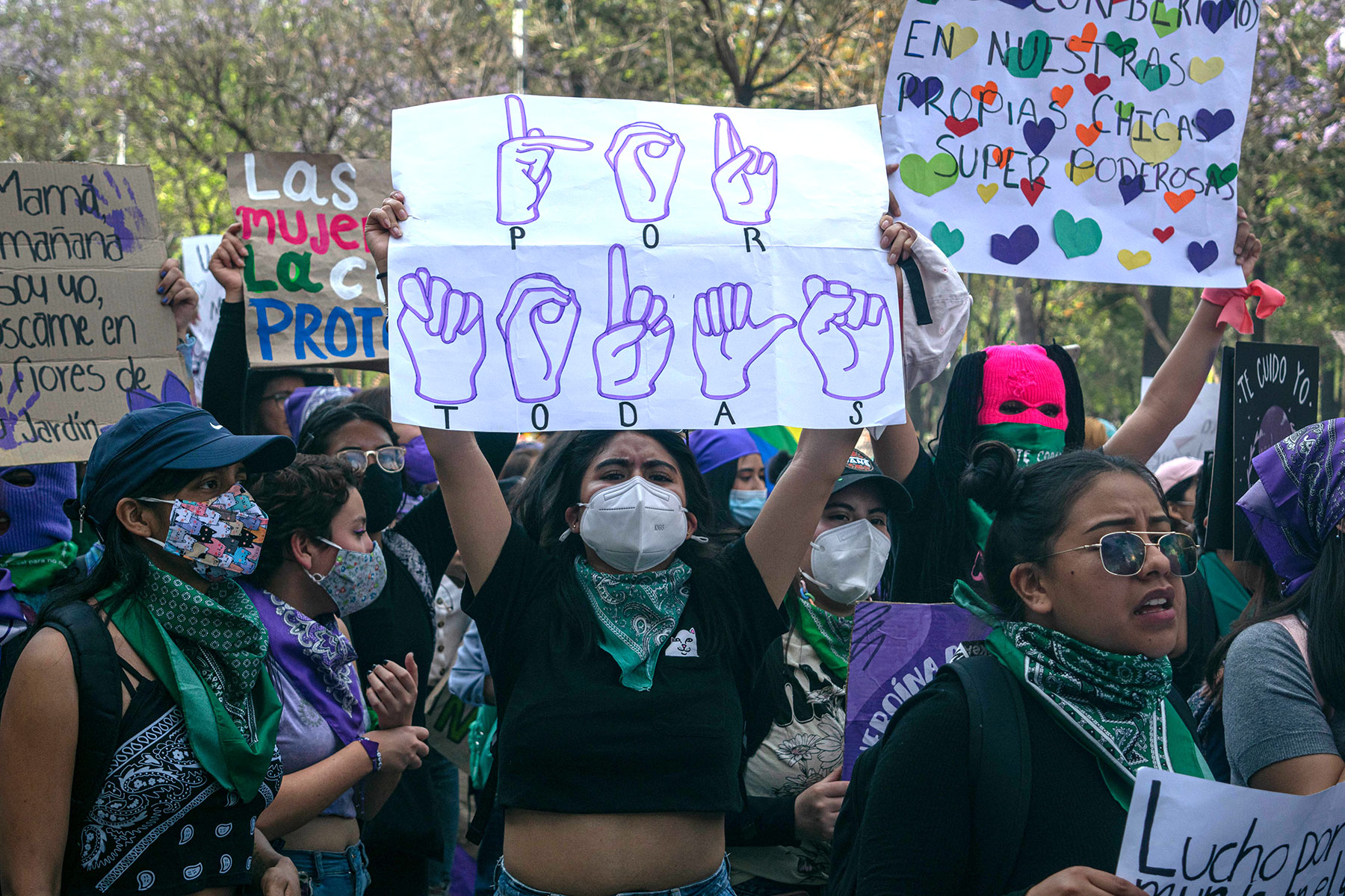 Fotografía. Pancarta en Lengua de Señas Mexicana en la marcha del #8M de 2022 en la Ciudad de México. Descripción: Una mujer en la marcha del 8M sostiene una cartulina que dice “Por todas” en Lengua de Señas Mexicana. Crédito: Lizbeth Lucio